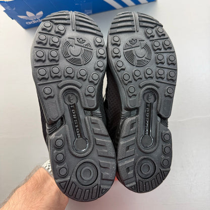 Adidas black trainers with sleek design and logo detail, perfect for kids.