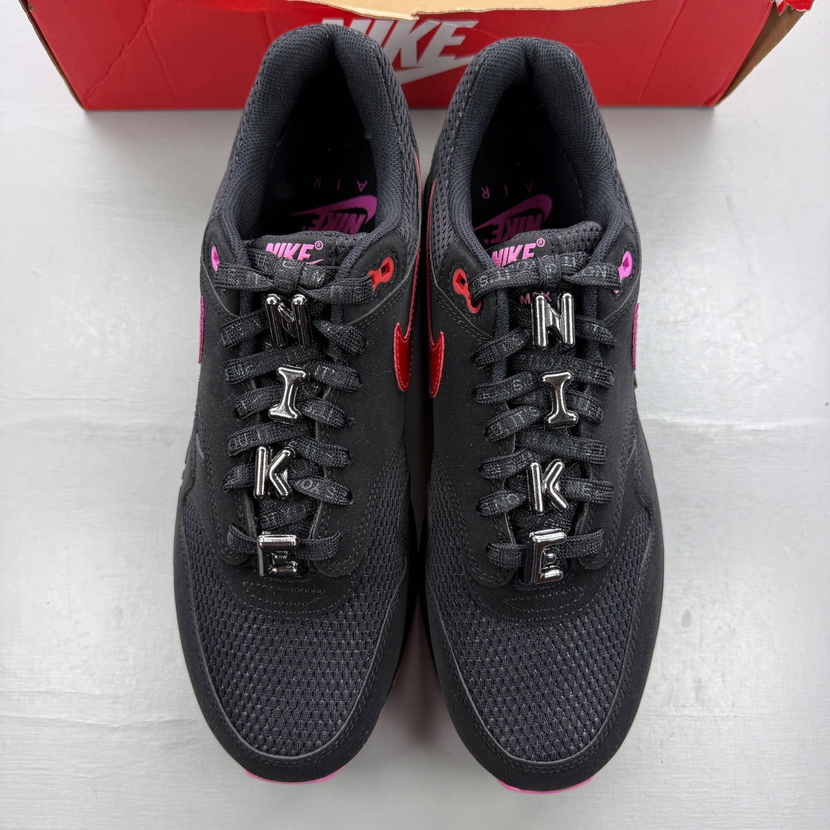 Nike trainers black with playful pink accents and Air Max cushioning.