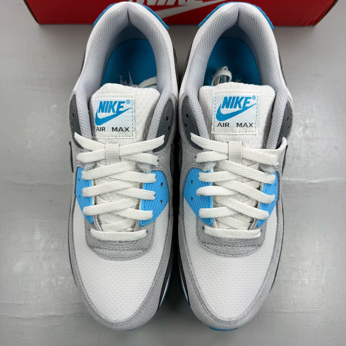 Nike Air Max 90 grey trainers with blue accents and signature swoosh logo.