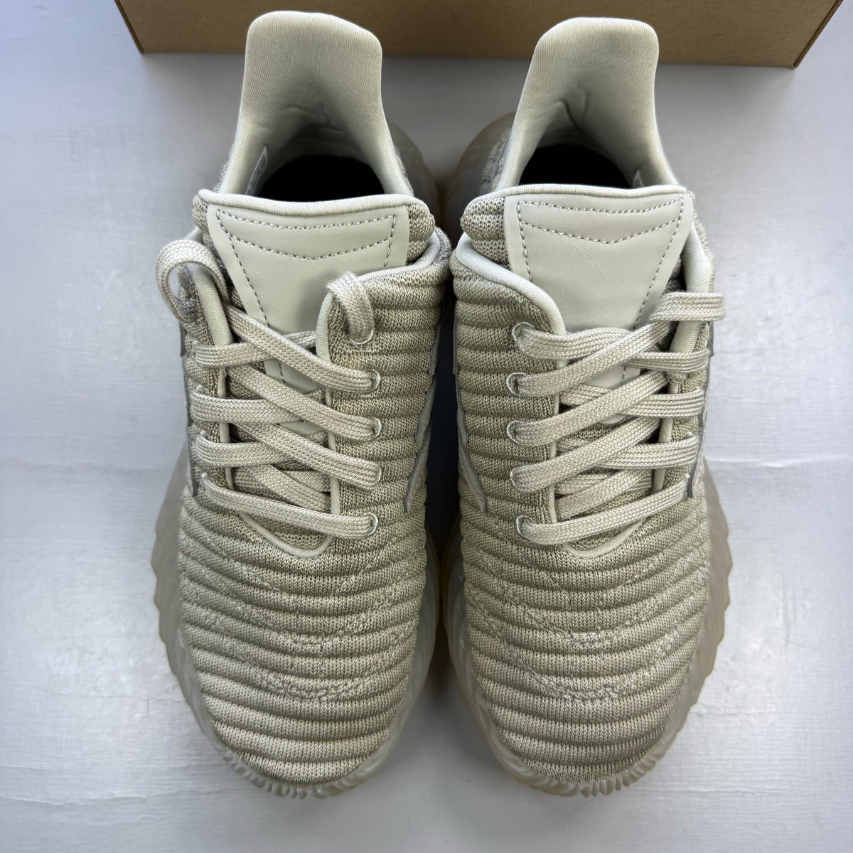 Adidas grey trainers with textured upper and distinctive three-stripe logo detail.