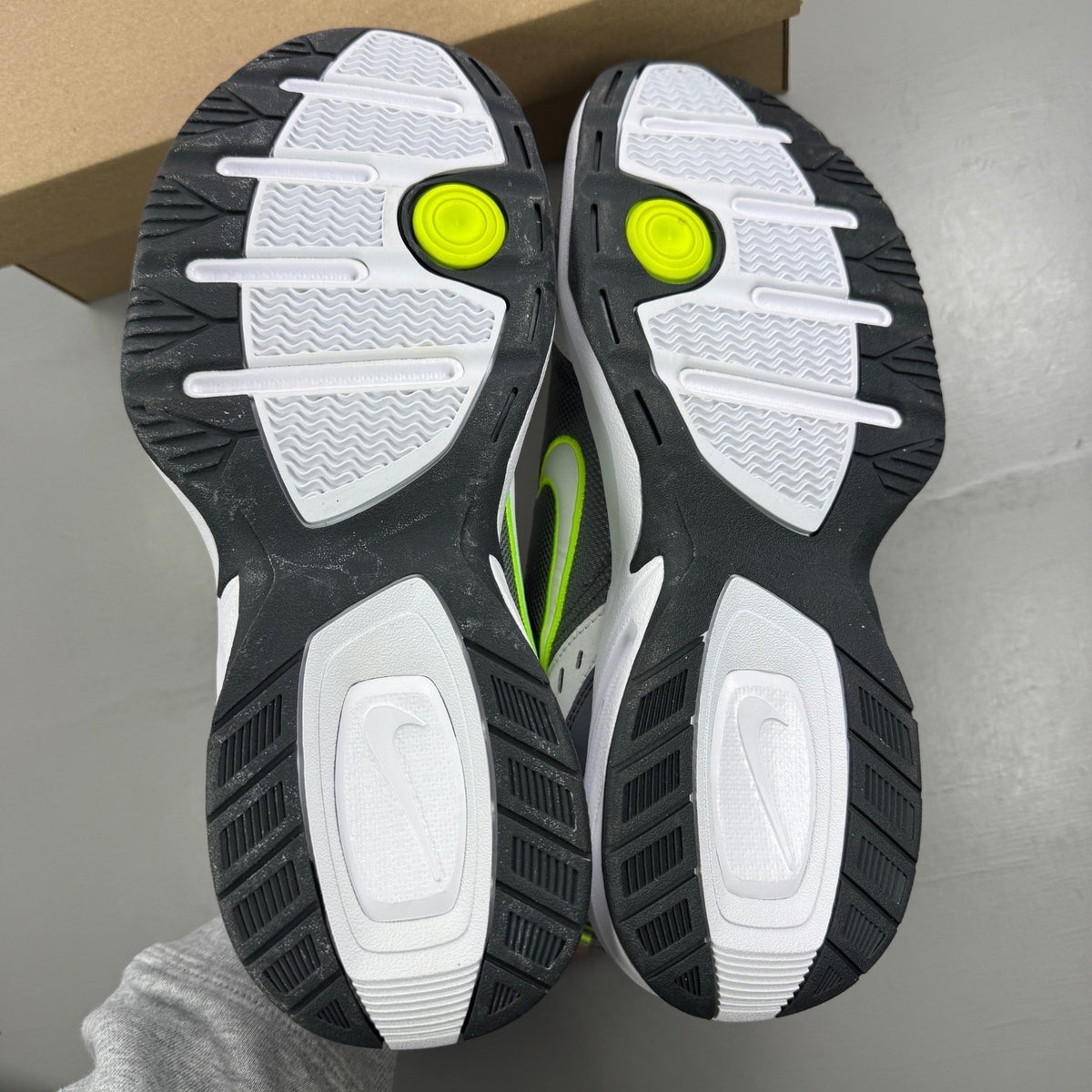 Nike Air Monarch IV white trainers with cool grey and green accents, featuring logo detail.