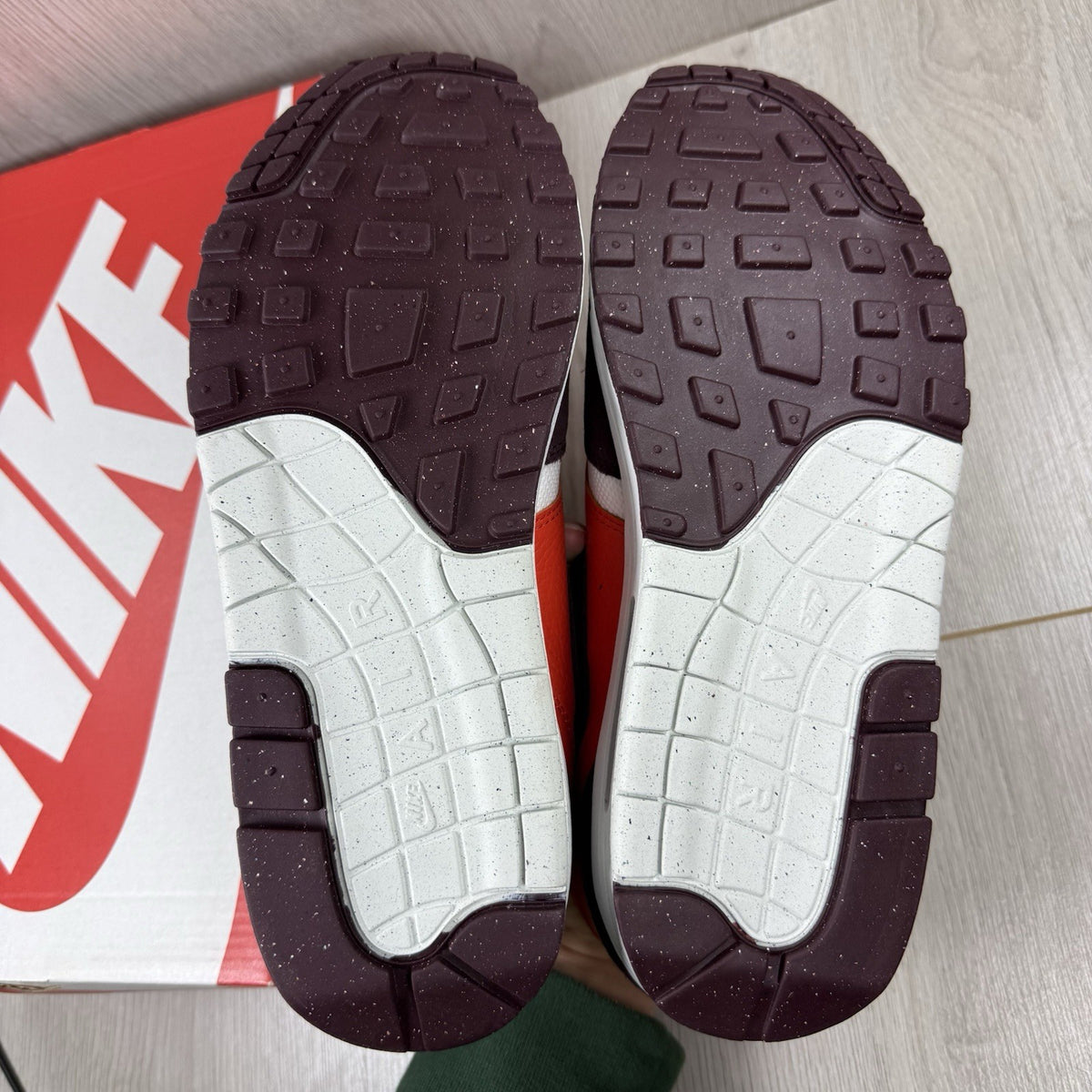 Nike Air Max 1 red trainers with white accents and signature swoosh logo.