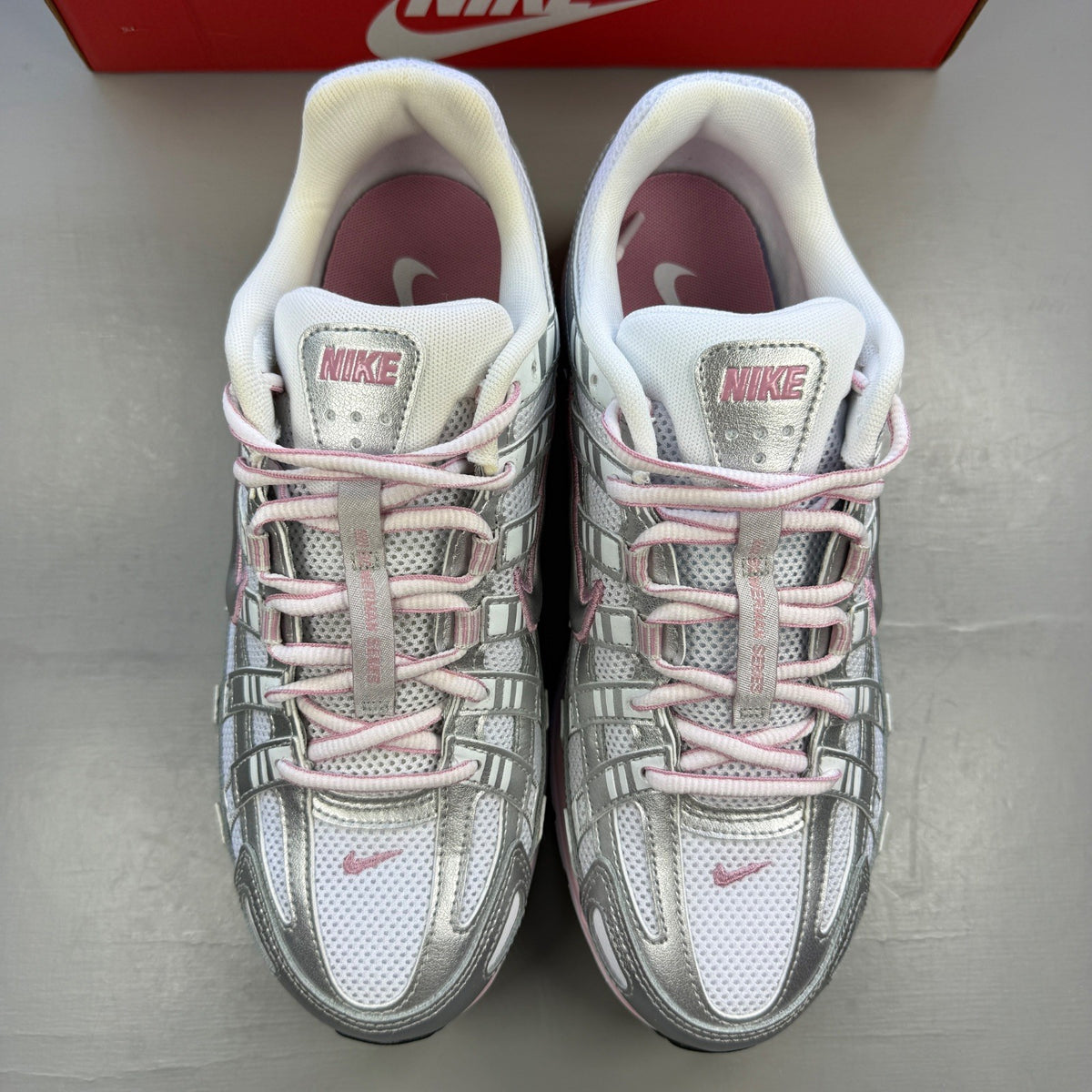 Nike white trainers with elemental pink and silver accents, featuring logo details.