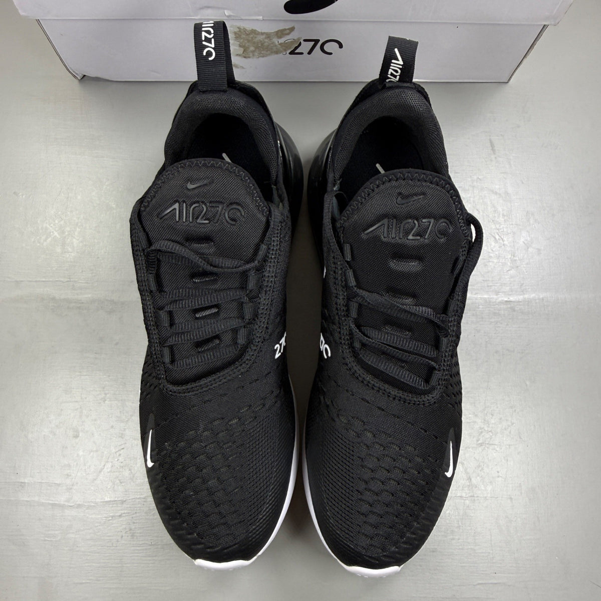 Nike Air Max 270 black trainers with white accents and logo detail.
