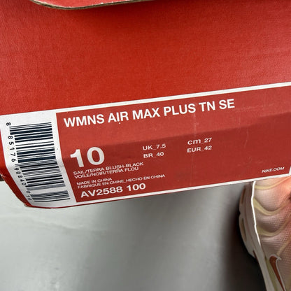 Nike Air Max Plus TN white trainers with peach accents and signature swoosh logo.