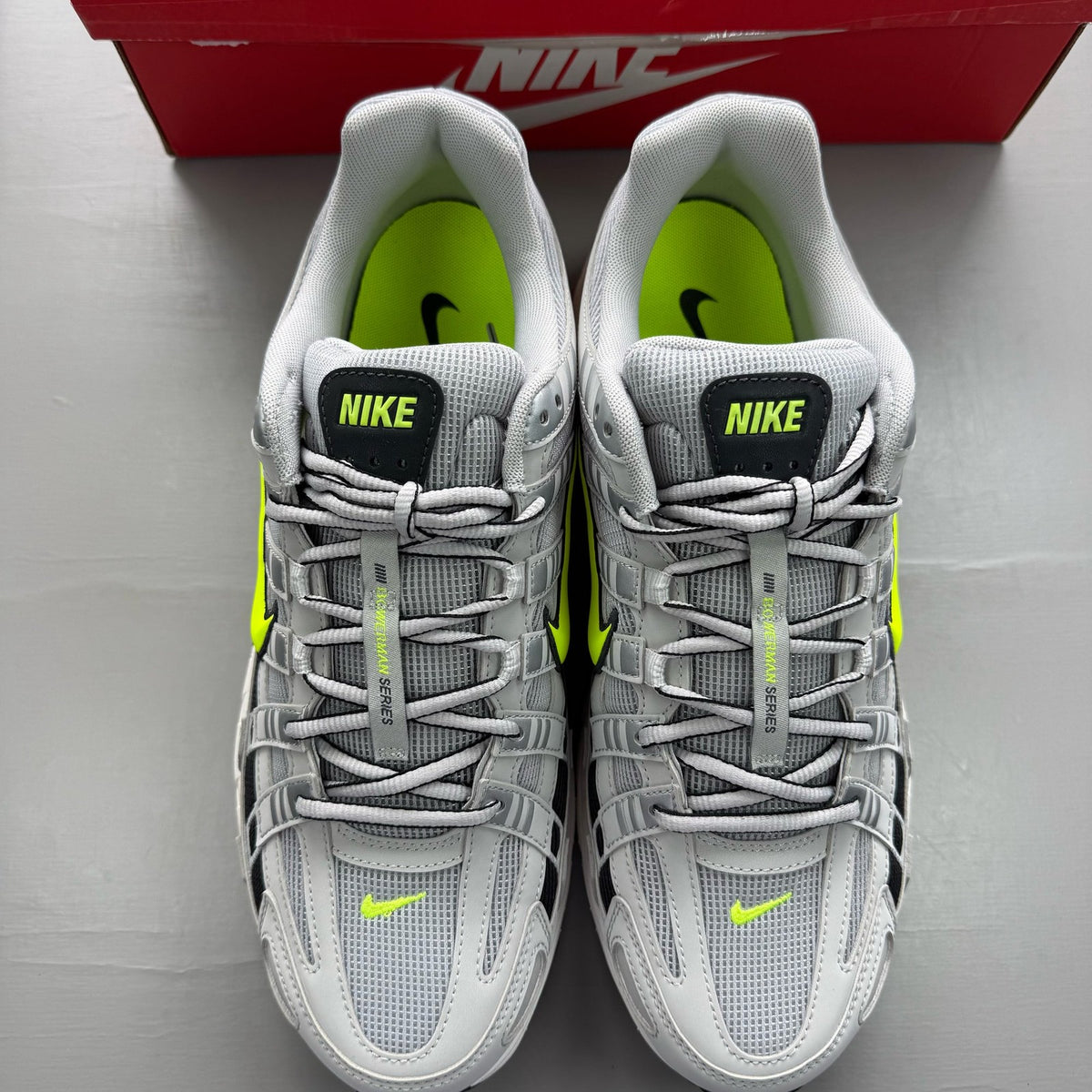 Nike P-6000 grey trainers with black accents and volt details, featuring iconic swoosh logo.