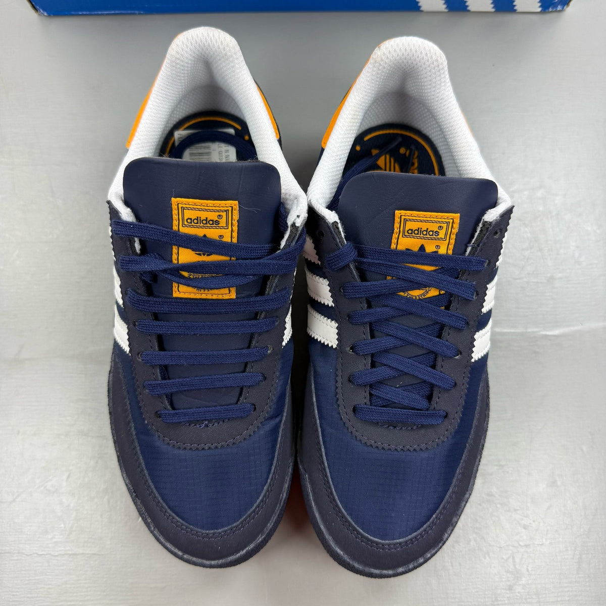 Adidas blue kids trainers with white and orange accents, featuring logo detail.