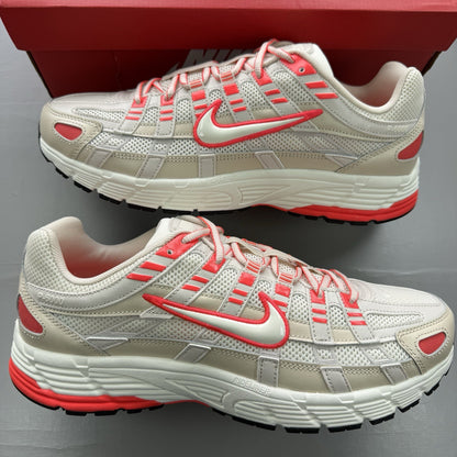 Nike white trainers with bright crimson red accents and soft pearl cream detailing.