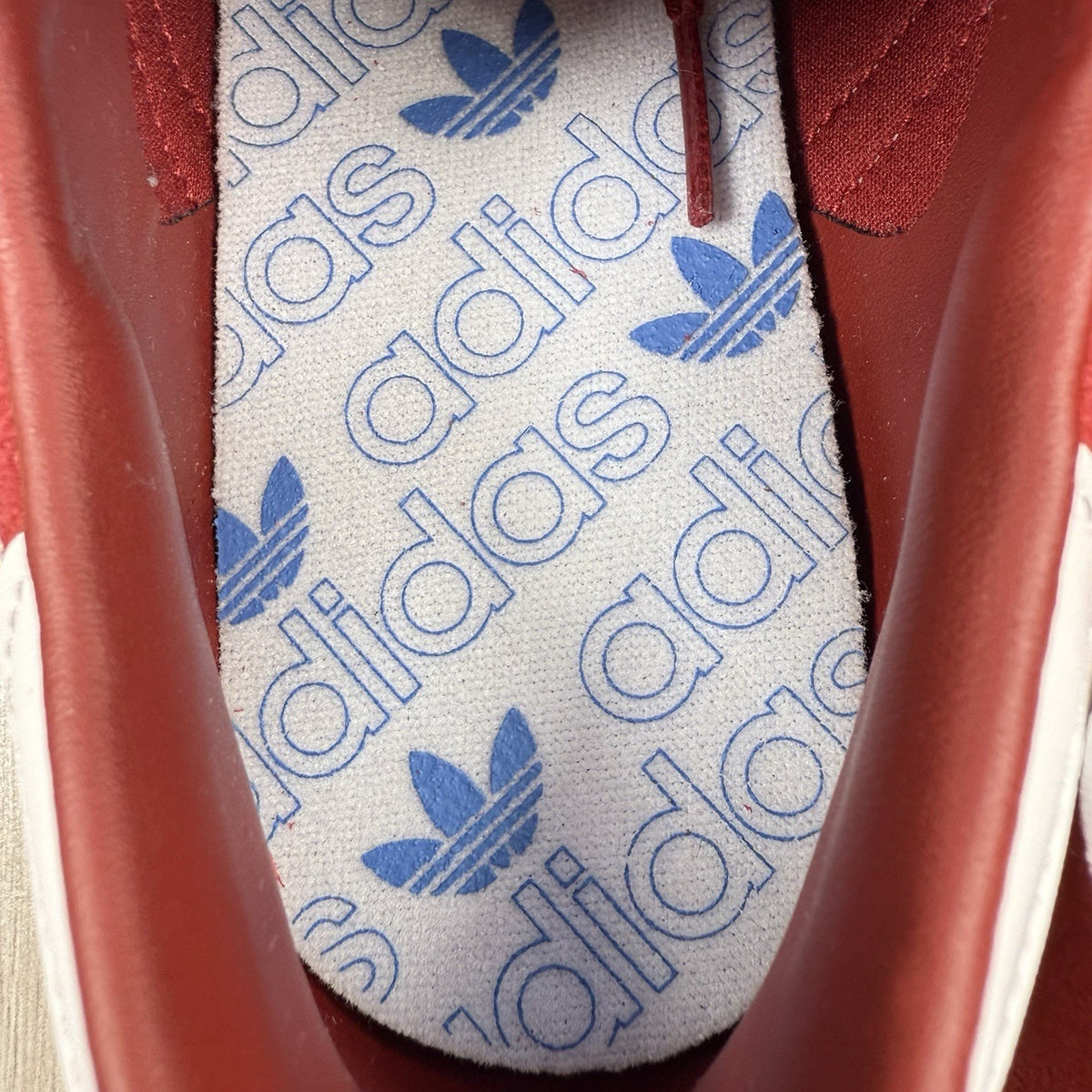 Adidas red trainers with white stripes and logo, classic suede material.