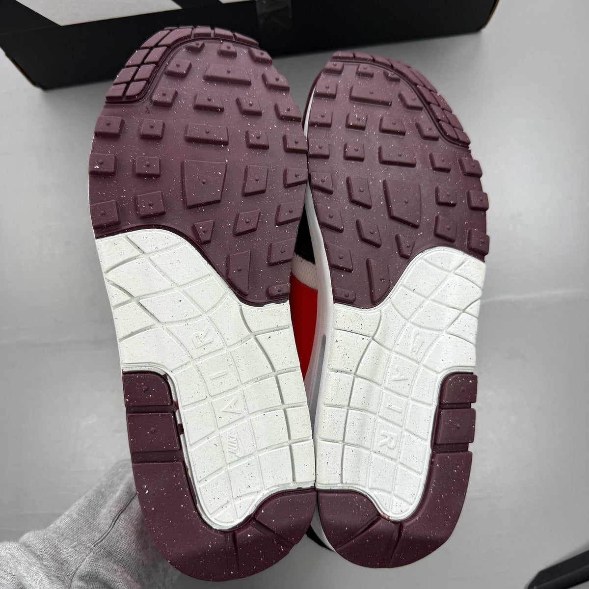 Nike Air Max 1 red trainers with white accents and logo detailing.