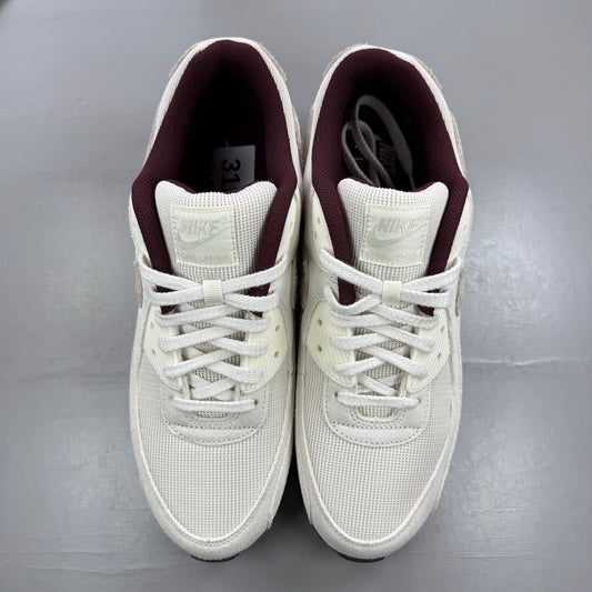 Nike Air Max 90 white trainers with burgundy accents and signature swoosh logo.