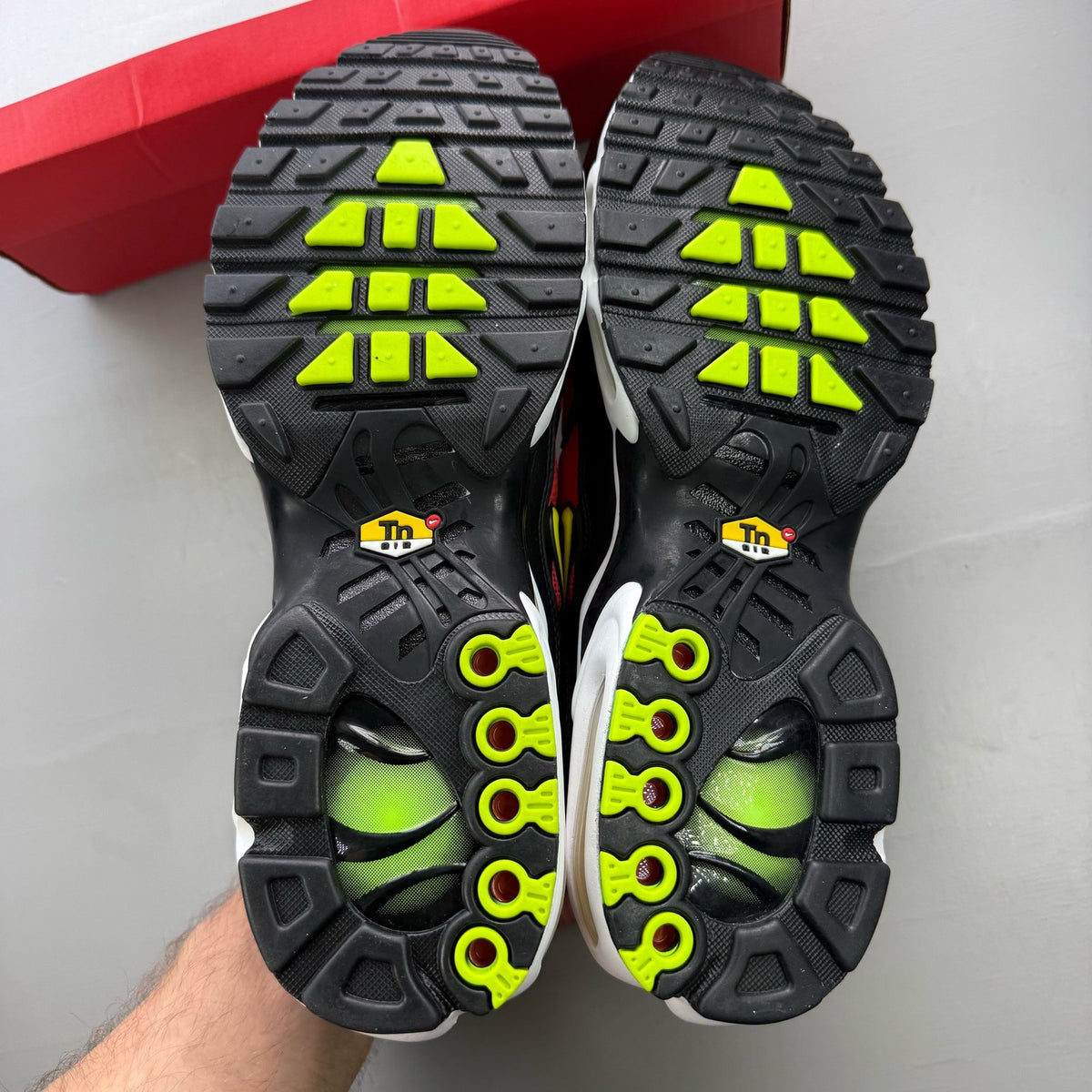 Nike Air Max Plus TN red trainers with black accents and vibrant volt detailing.
