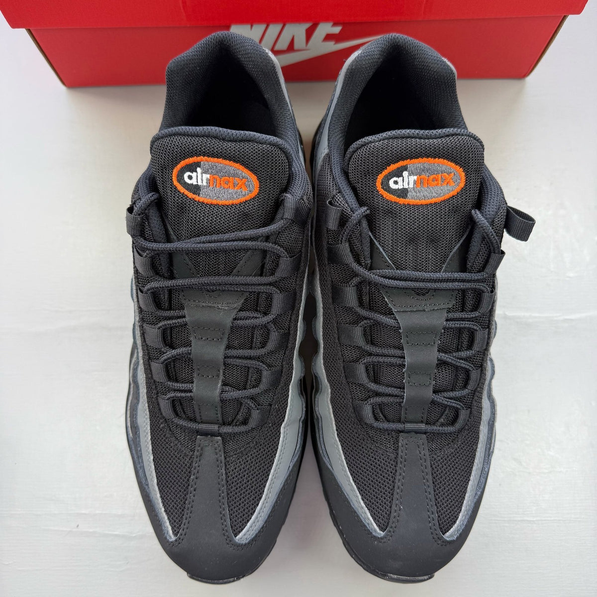 Nike Air Max 95 black grey trainers with safety orange accents and logo detailing.