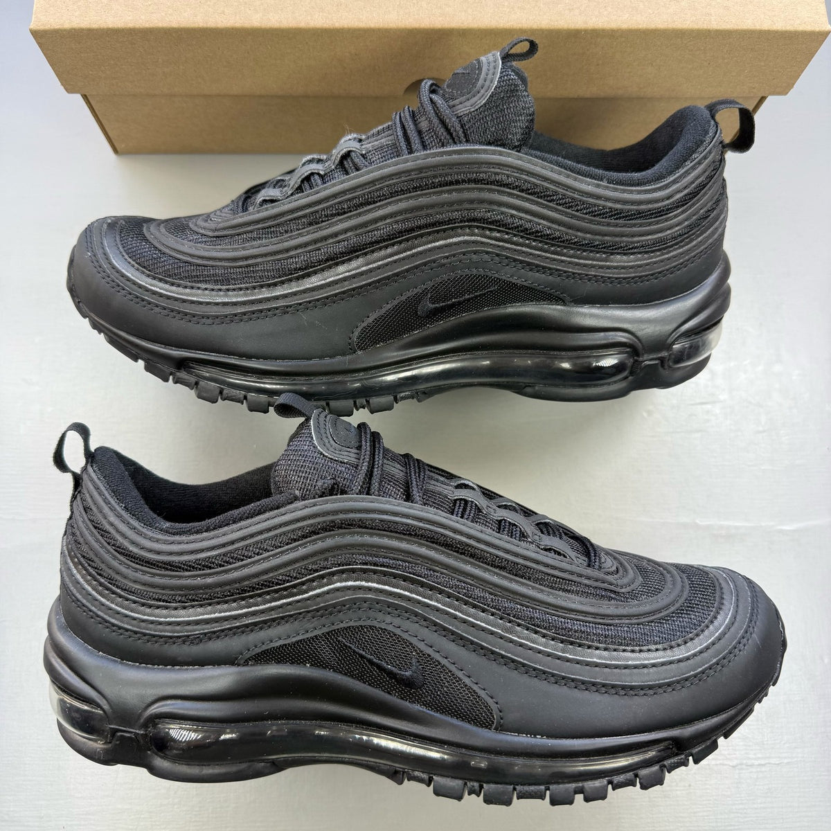 Nike Air Max 97 black low top trainers with sleek design and signature logo.