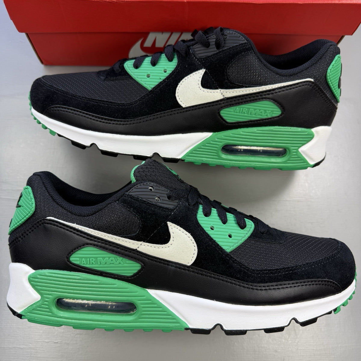 Nike Air Max 90 black trainers with stadium green accents and white sole.