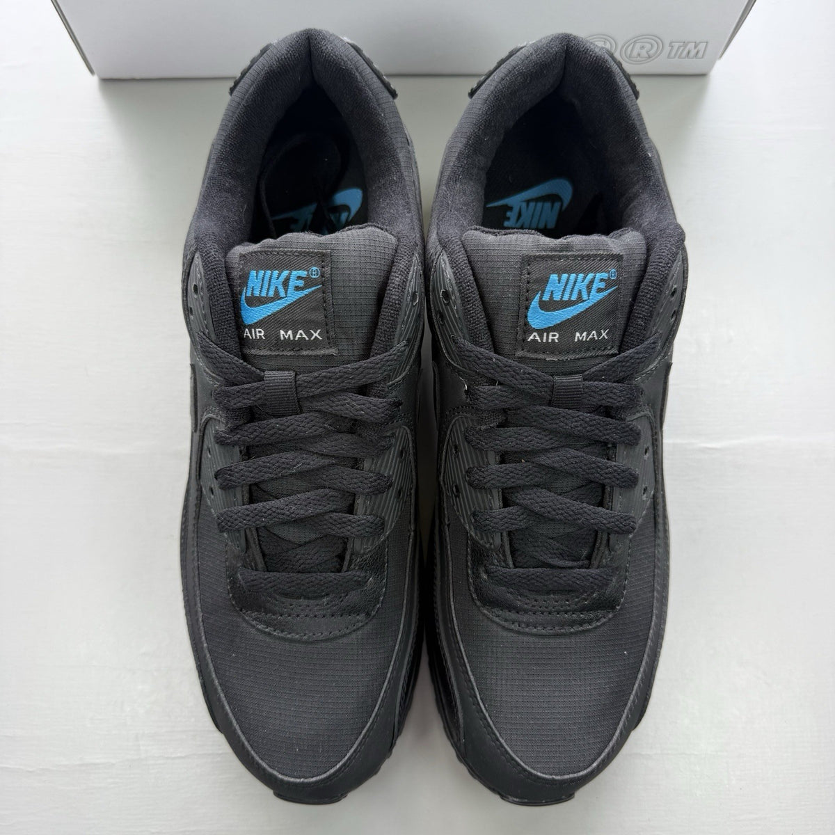 Nike Air Max 90 black trainers with laser blue accents and signature logo.