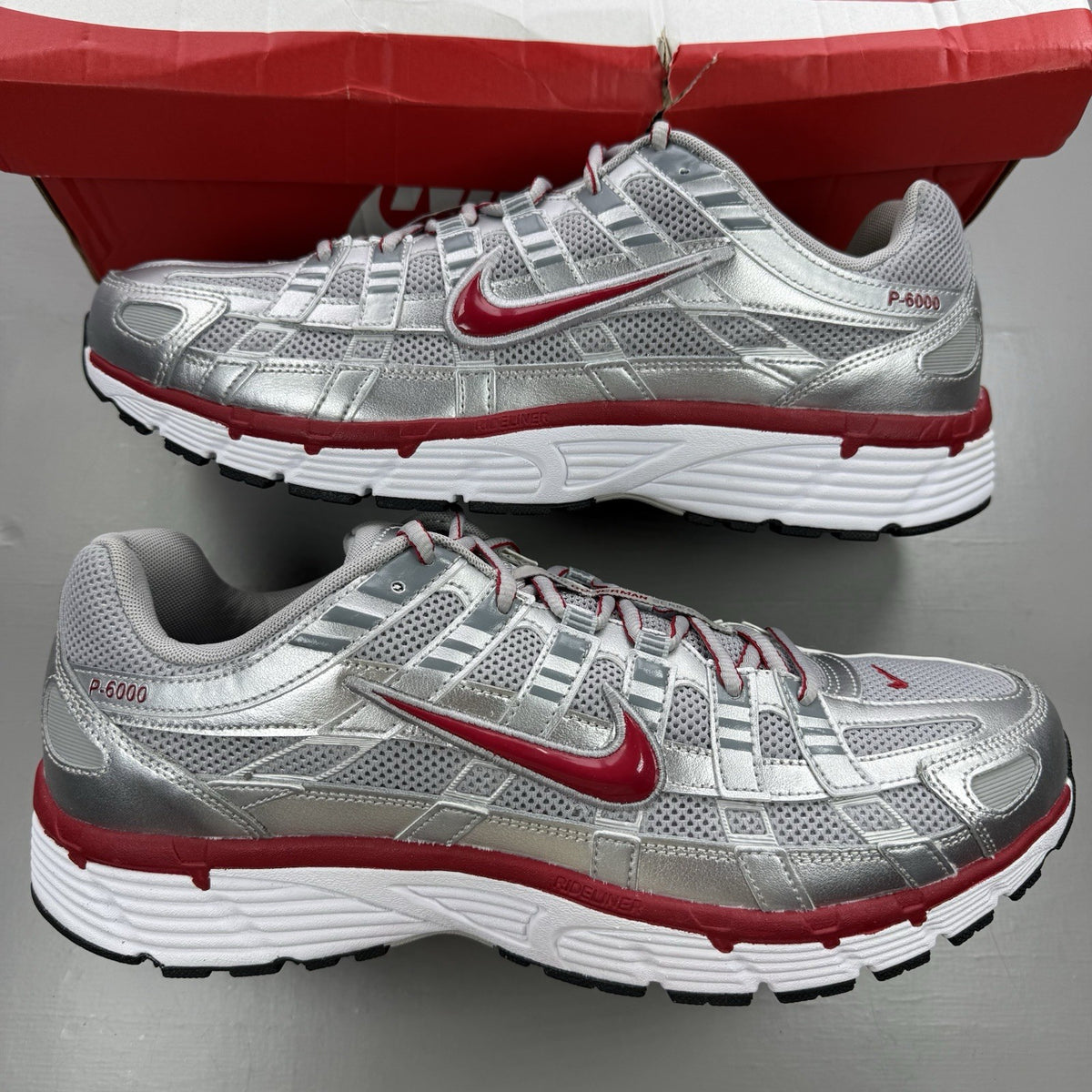 Nike P-6000 trainers in metallic silver with red and black accents, mesh upper.