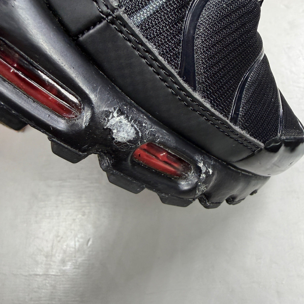 Nike Air Max Plus TN black trainers with red accents and iconic Tuned Air sole.