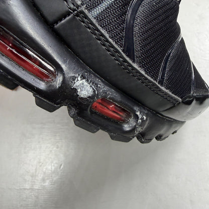 Nike Air Max Plus TN black trainers with red accents and iconic Tuned Air sole.