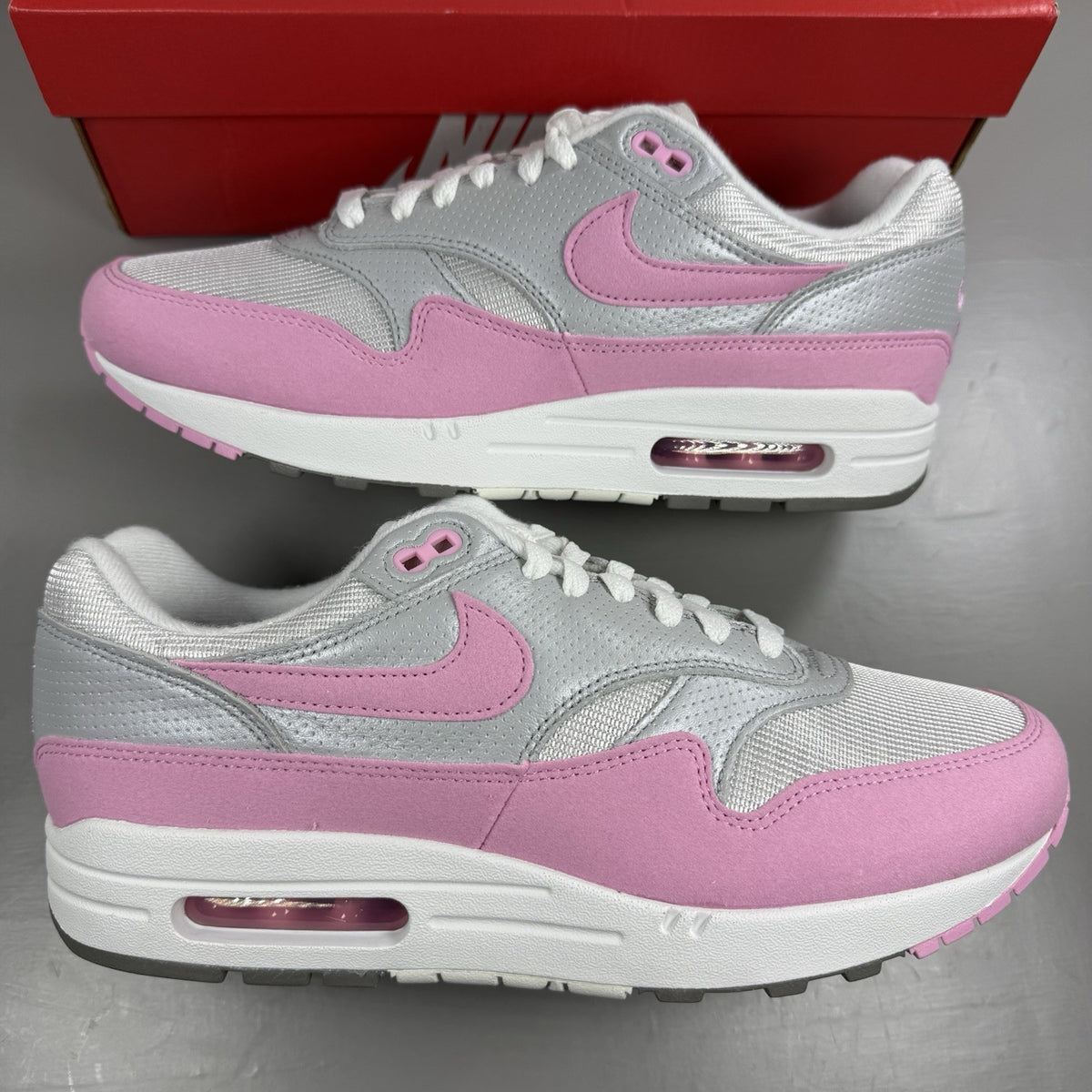 Nike Air Max 1 trainers pink with metallic accents and classic logo detailing.