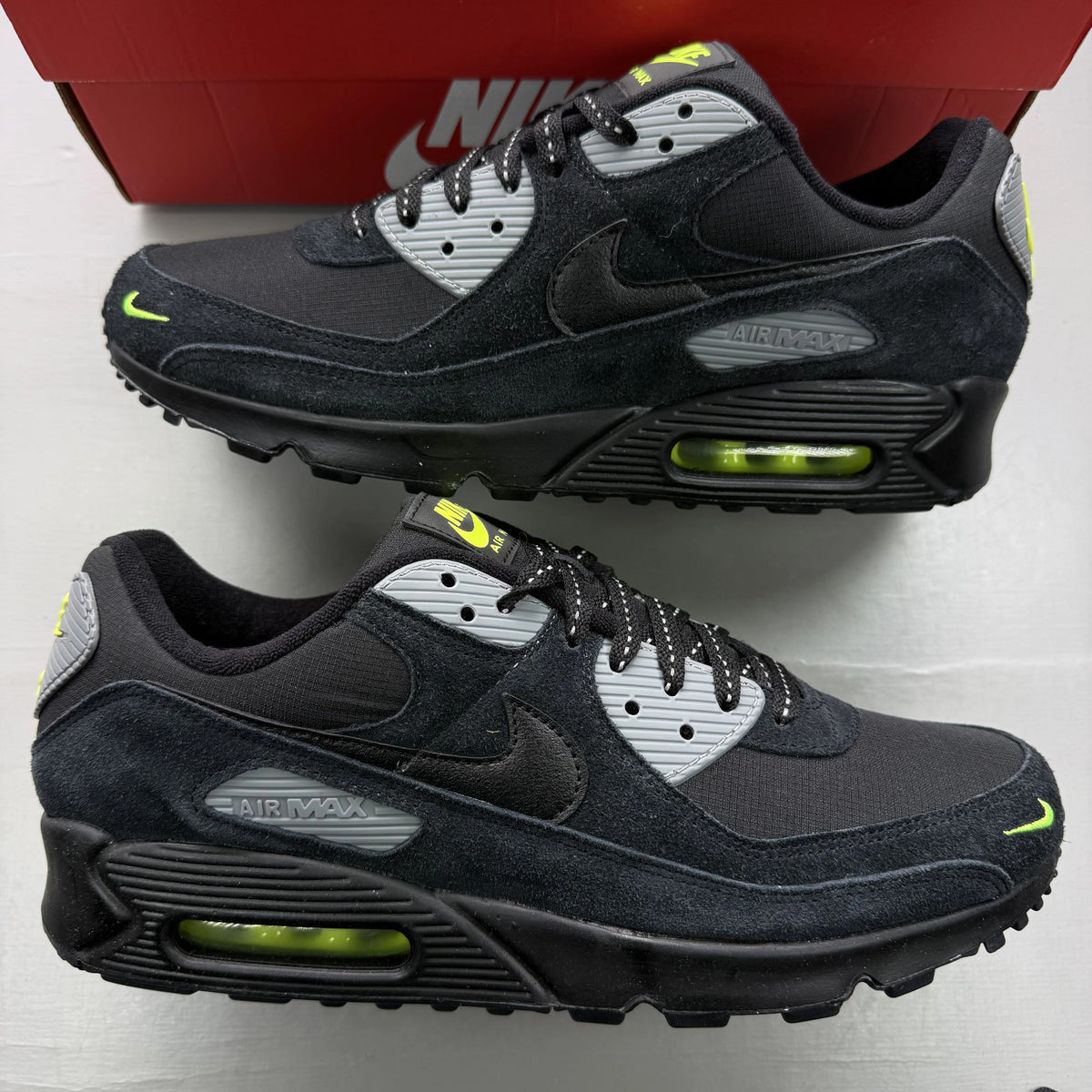 Nike Air Max 90 black trainers with volt and cool grey swoosh logo.