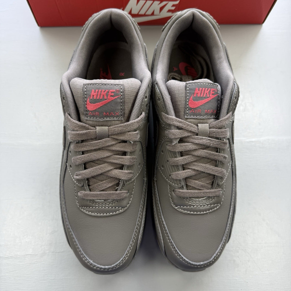 Nike Air Max 90 trainers grey with red accents and logo detail.