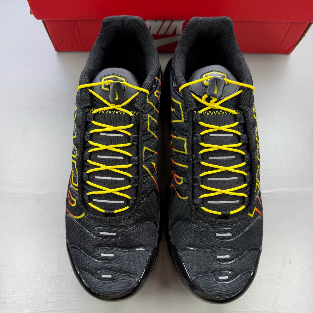 Nike black trainers with Tuned Air technology and sunrise pattern accents.