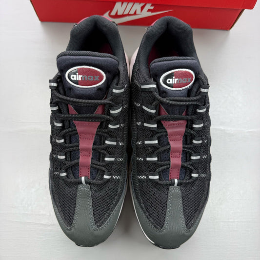 Nike black trainers with red accents and grey detailing, featuring iconic Air Max design.