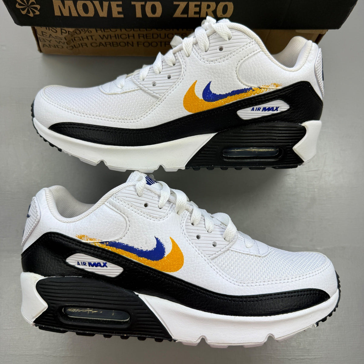 Nike Air Max 90 white athletic shoes featuring double swoosh logo and sleek design.