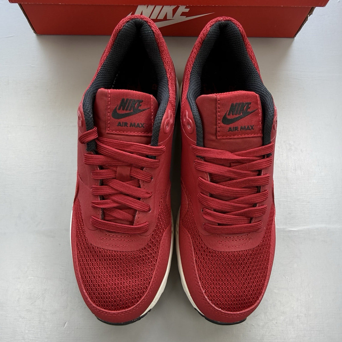 Nike Air Max 1 Ultra Essential red trainers with white and black accents, logo detail.