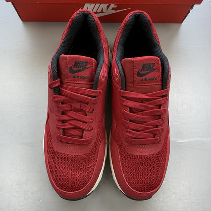 Nike Air Max 1 Ultra Essential red trainers with white and black accents, logo detail.