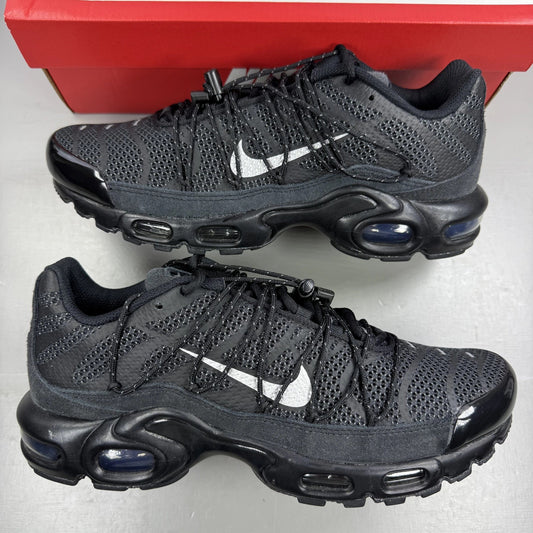 Nike black trainers with reflective silver accents and iconic Air Max Plus design.