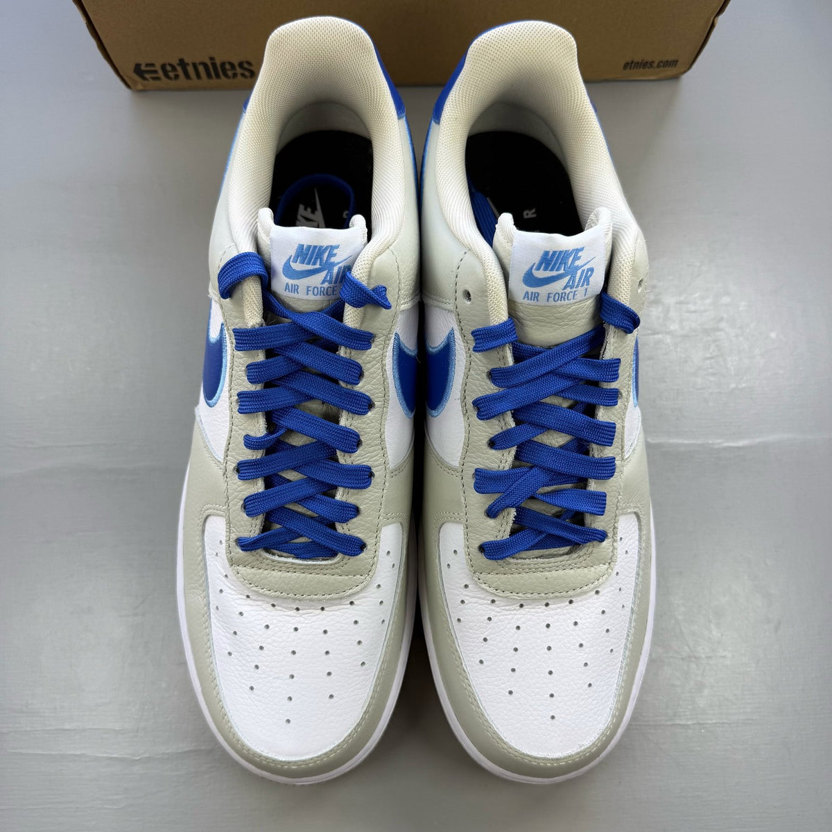 Nike Air Force 1 low trainers white with blue accents and gum sole.