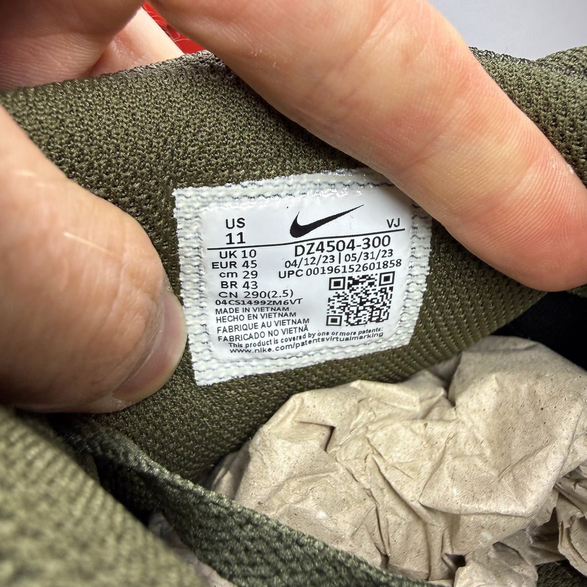 Nike Air Max 90 olive green trainers with reflective detailing and black accents.