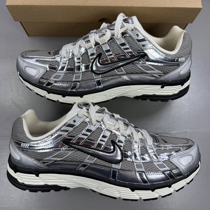 Nike athletic shoes metallic silver with mesh upper and reflective detailing.