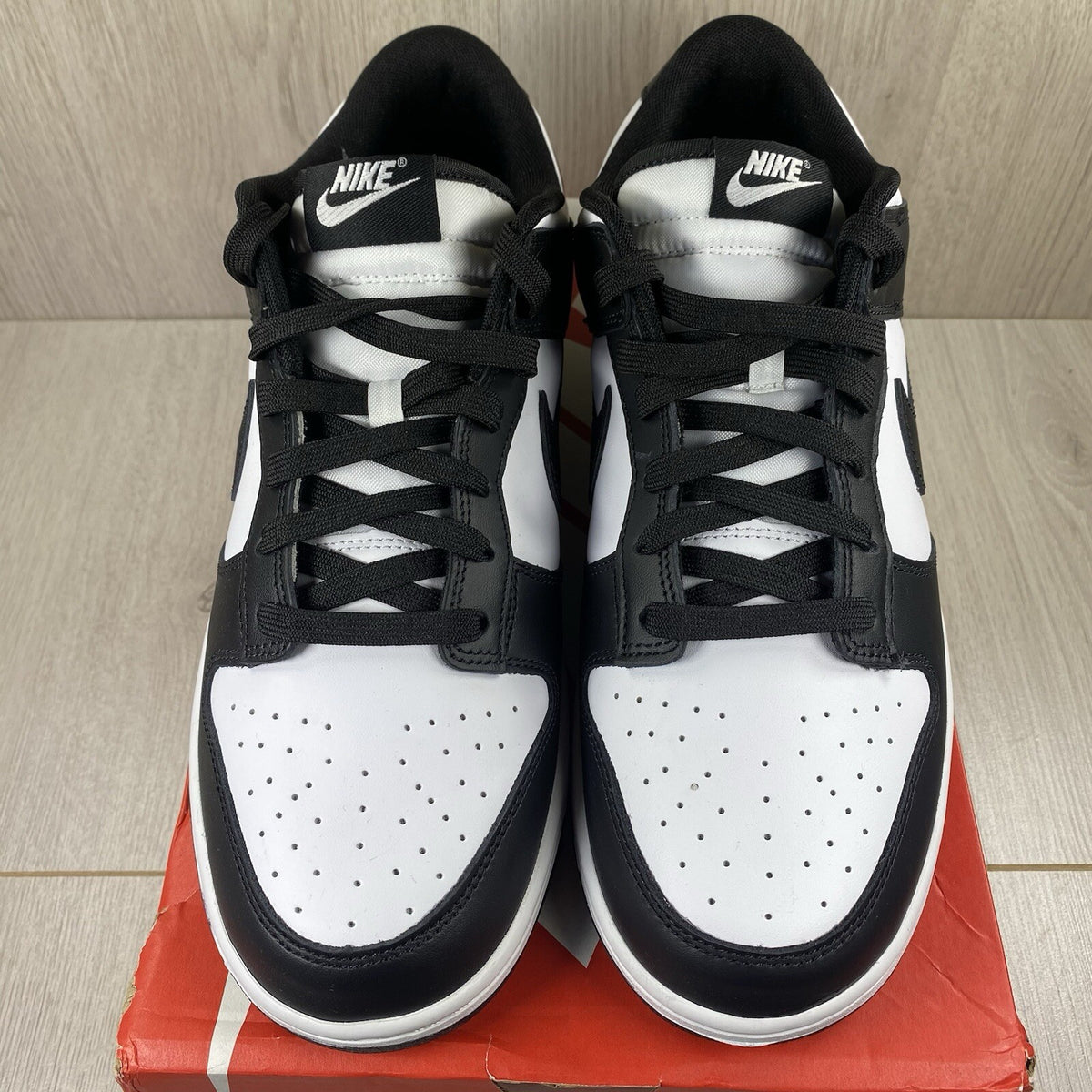 Nike Dunk Low trainers black and white with iconic swoosh logo and smooth leather upper.
