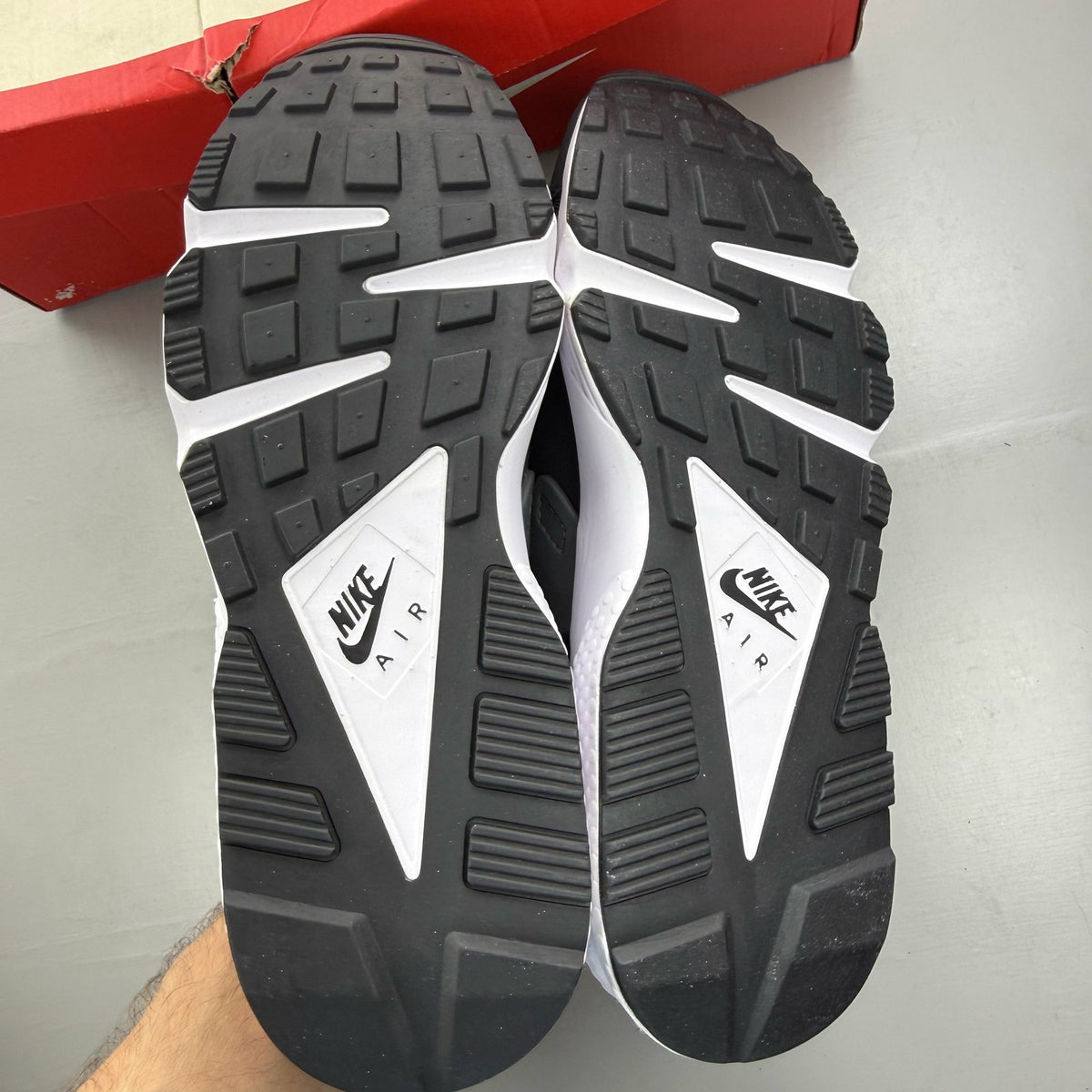 Nike black Air Huarache trainers with safety orange accents and white sole.