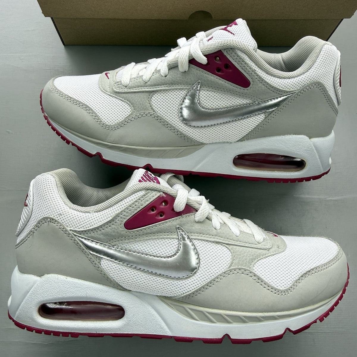 Nike Air Max Correlate white trainers with fuchsia accents and logo detailing.
