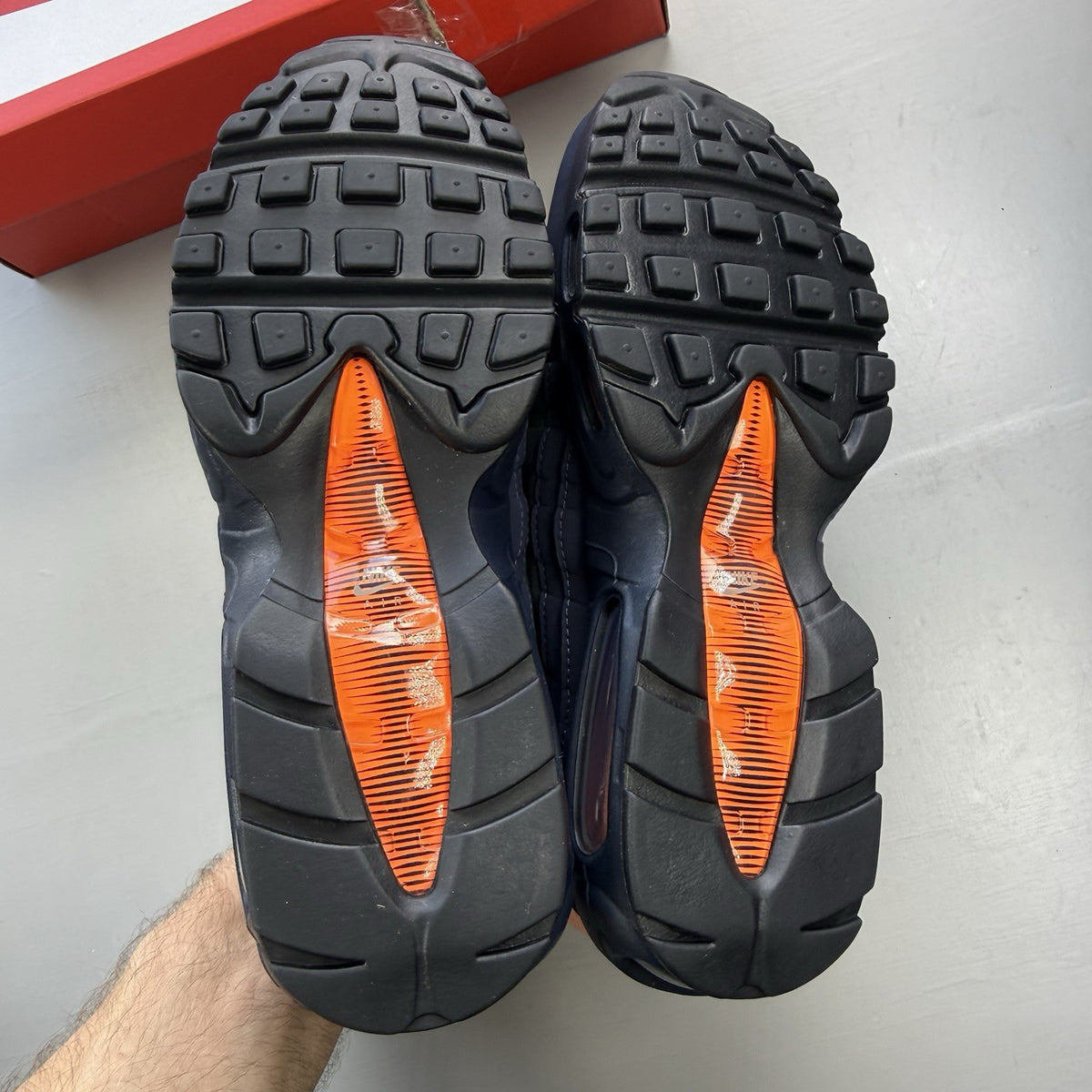 Nike Air Max 95 trainers navy blue with orange accents and anthracite grey details.