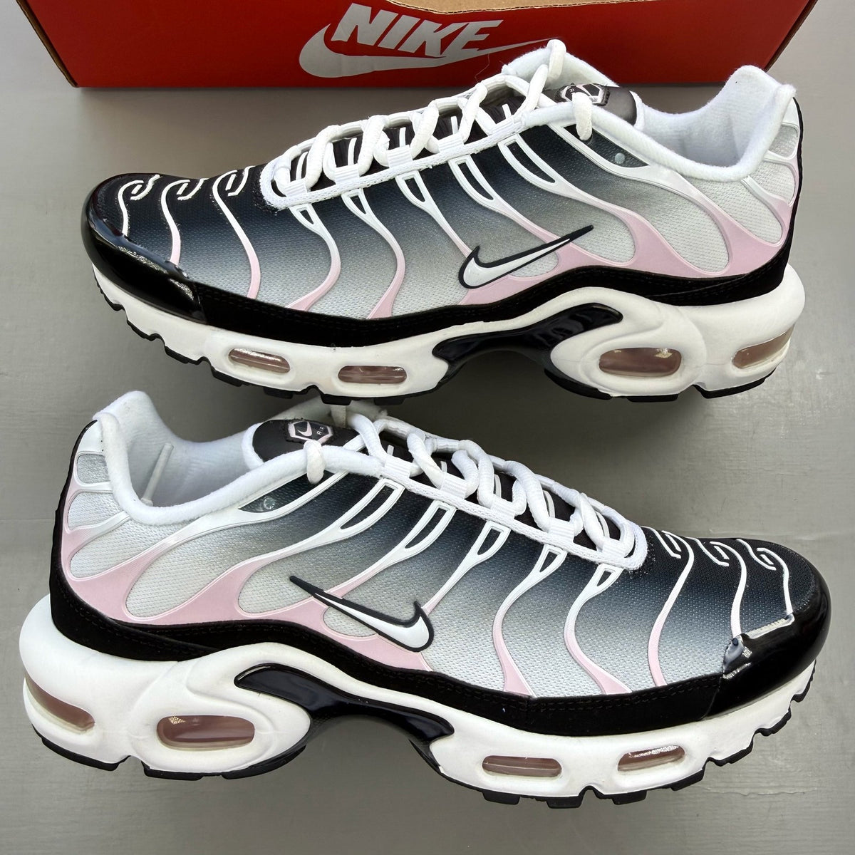 Nike trainers white with pink accents and black detailing, featuring Air Max cushioning.