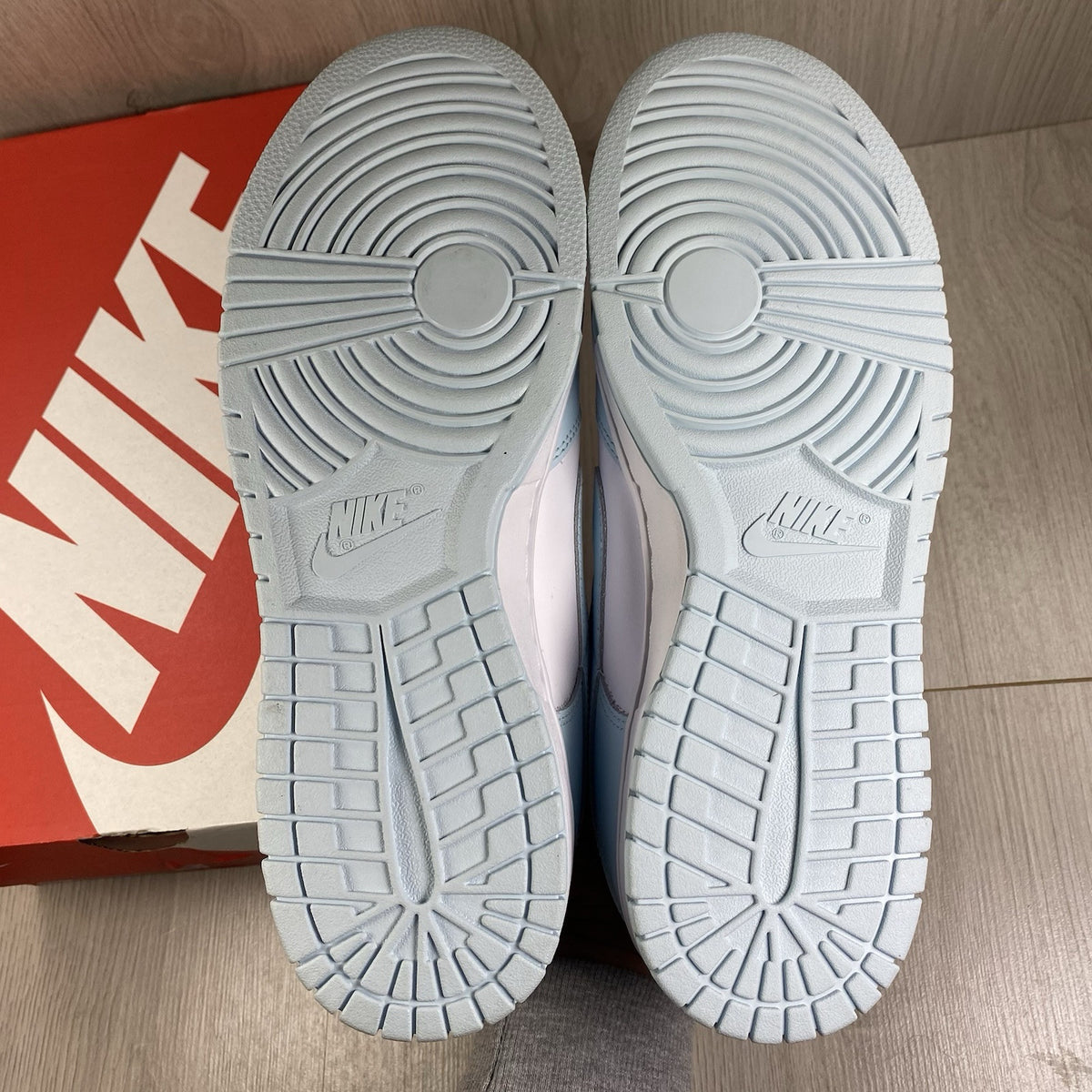 Nike Dunk Low Retro trainers glacier blue with white swoosh logo and textured material.