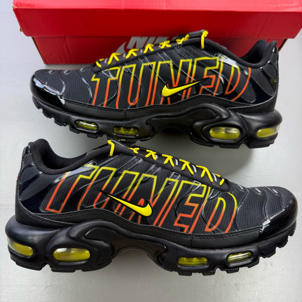 Nike black trainers with Tuned Air technology and sunrise pattern accents.