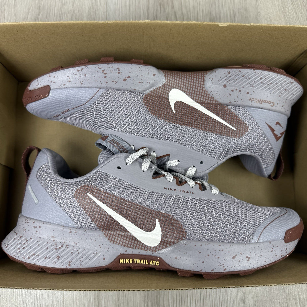Nike grey trainers with dark pony accents and textured material.