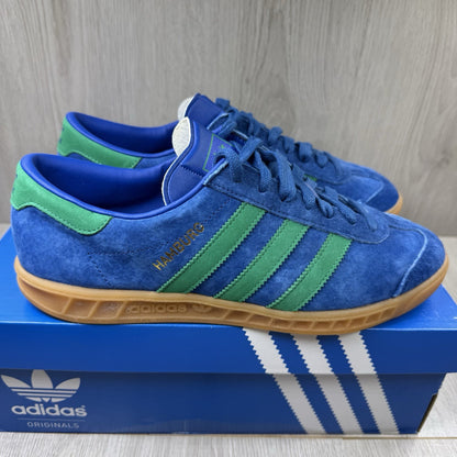 Adidas blue trainers with gum sole and iconic three-stripe logo design.