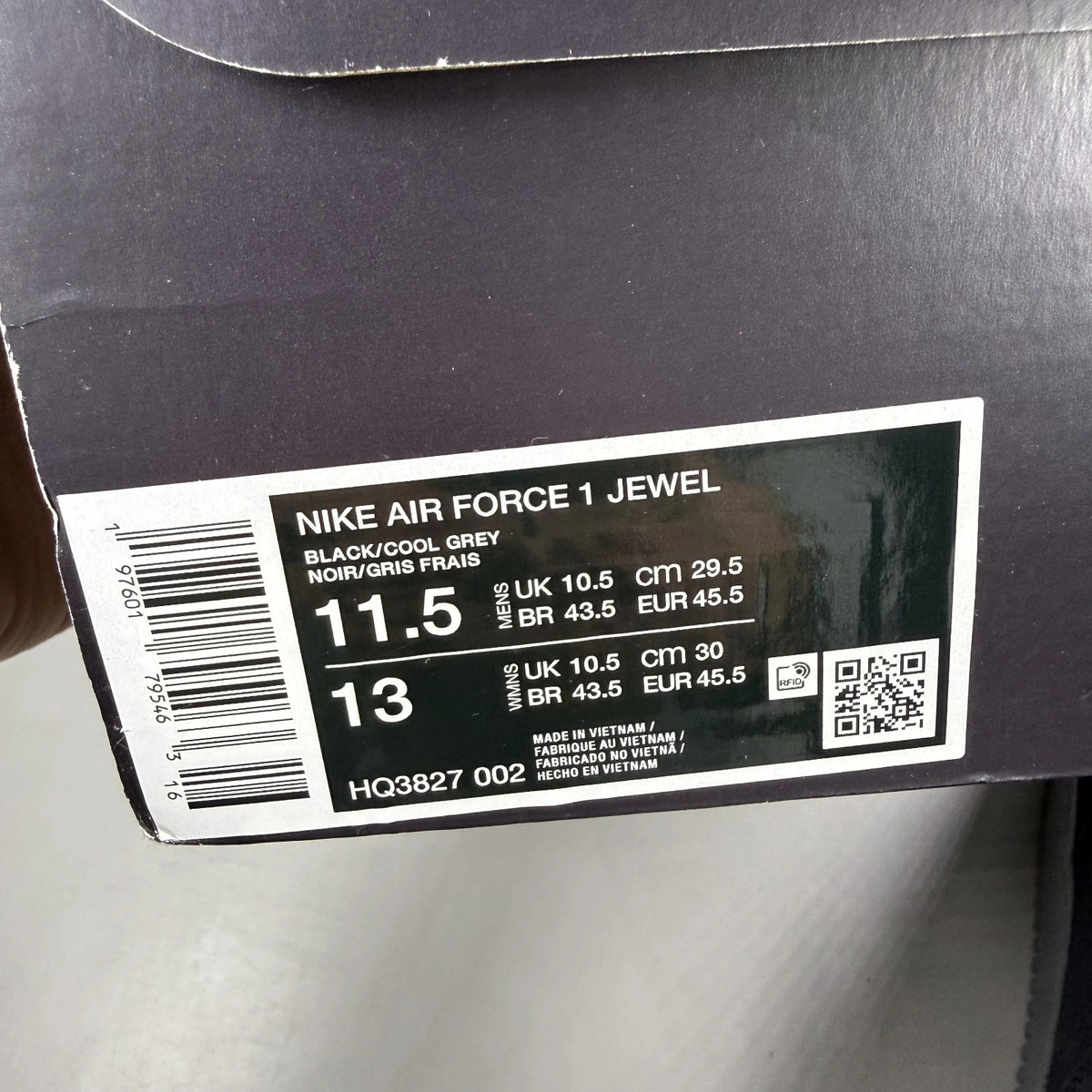 Nike Air Force 1 black trainers with cool grey accents and jewel detailing.
