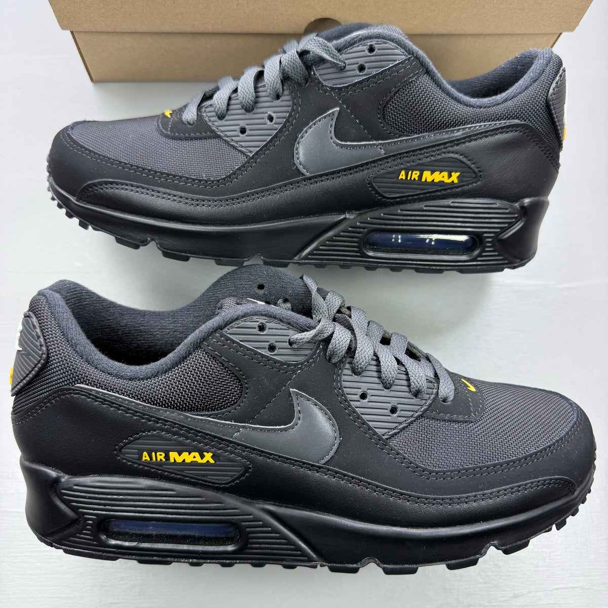 Nike Air Max 90 black trainers with speed yellow accents and signature logo details.