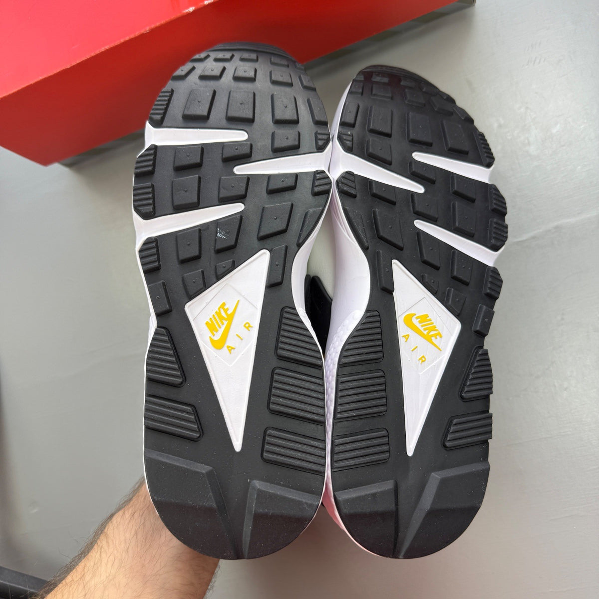 Nike Air Huarache white sneakers with yellow maize and navy accents, featuring logo details.