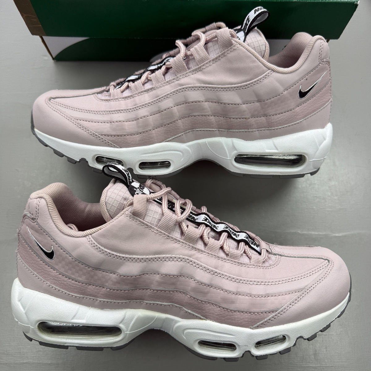 Nike trainers pink with white accents and Air Max cushioning details.