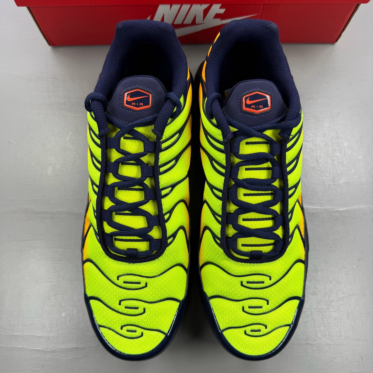 Nike yellow trainers with Hyper Crimson accents and distinctive Air Max Plus design.