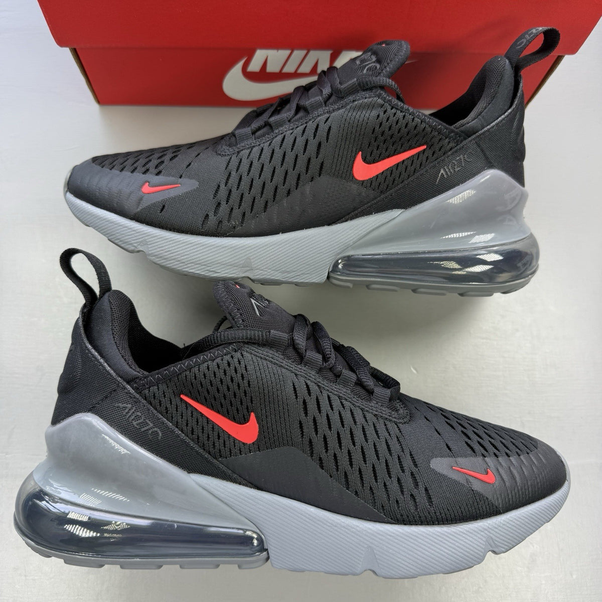 Nike Air Max 270 BG black trainers with crimson red accents and grey detailing.